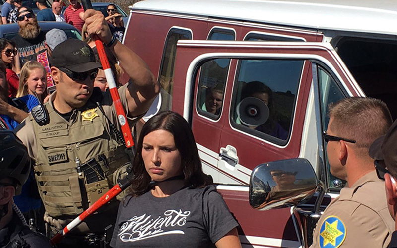 A Maricopa County Sheriff deputy cuts free a protester who locked herself to a van Saturday morning in the middle of Shea Blvd. in an attempt to stop supporters of presidential candidate Donald Trump from reaching his rally in Fountain Hills. (Photo by Justin Emerson/Cronkite News)