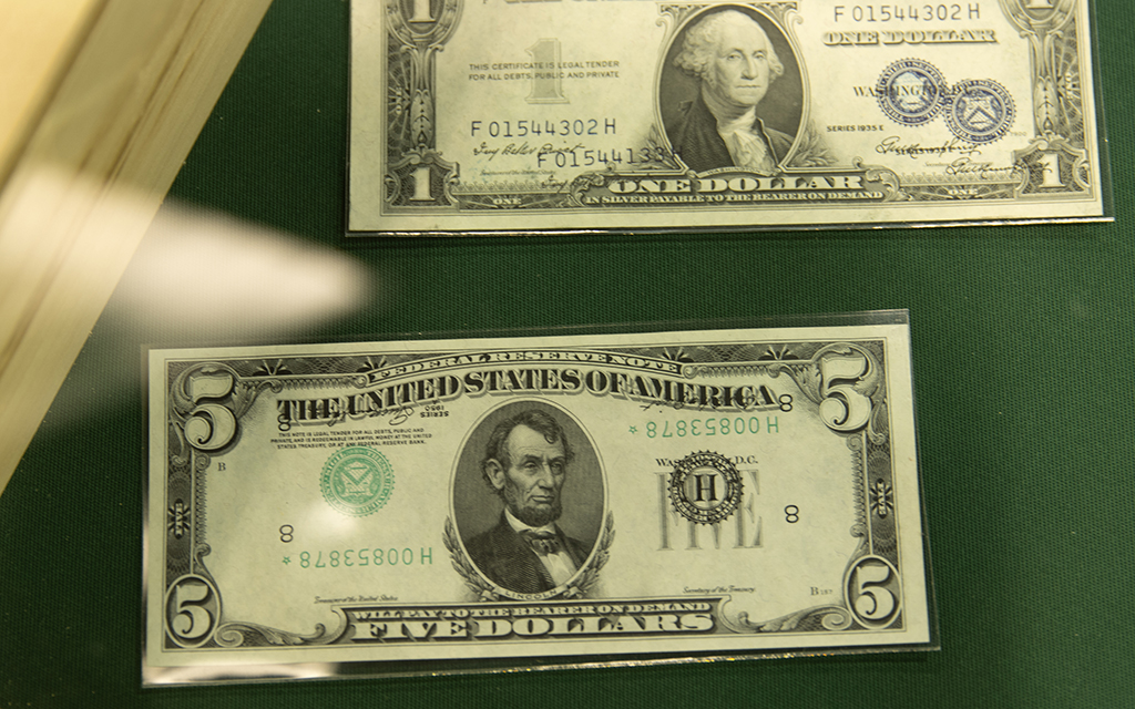 A misprinted $5 bill with upside-down serial numbers and a $1 bill with double serial numbers are on display at the 2023 National Money Show, hosted by the American Numismatic Association at the Phoenix Convention Center on March 2, 2023. (Photo by Lydia Curry/Cronkite News)