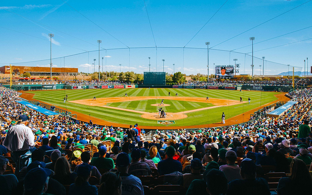 Spectators sit behind home plate at Camelback Ranch and watch a baseball game.