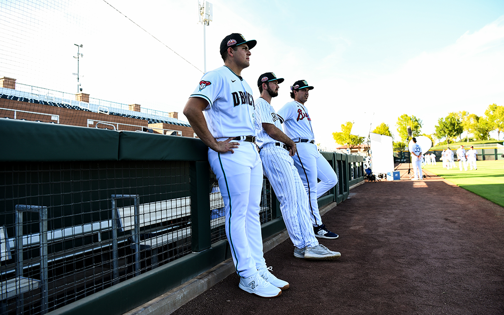 Ivan Melendez and other players leaning against the dugout.