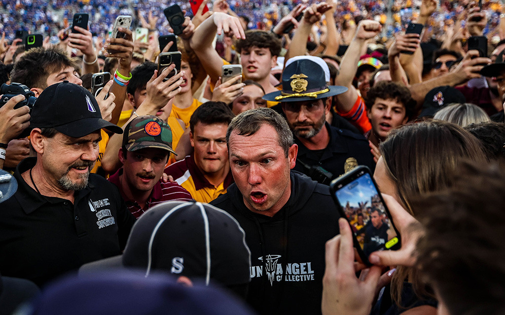 Arizona State coach Kenny Dillingham talking to game officials surrounded by fans.