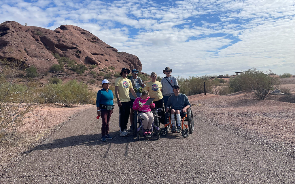 A set of hikers stand together in front of the mountains at Papago Park