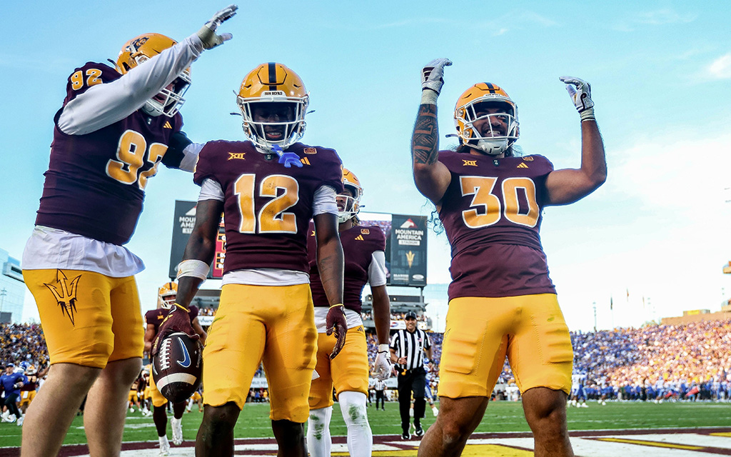 Three football players celebrating after a good play in front of a large crowd
