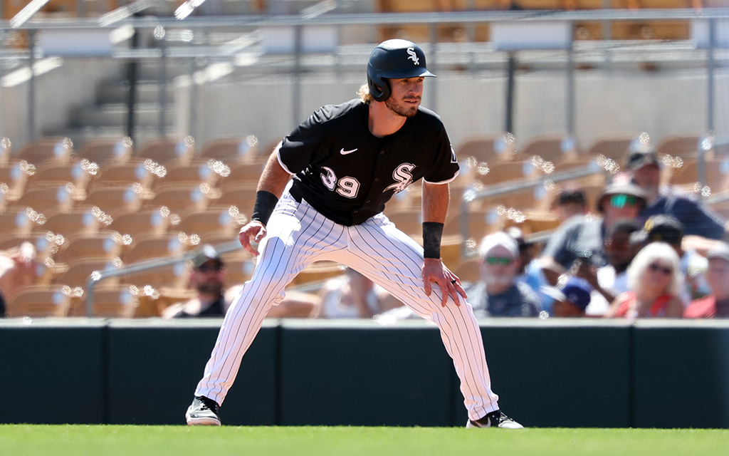 Travis Jankoski in a black jersey and white pinstripe pants, ready to run with a blurred crowd in the background.