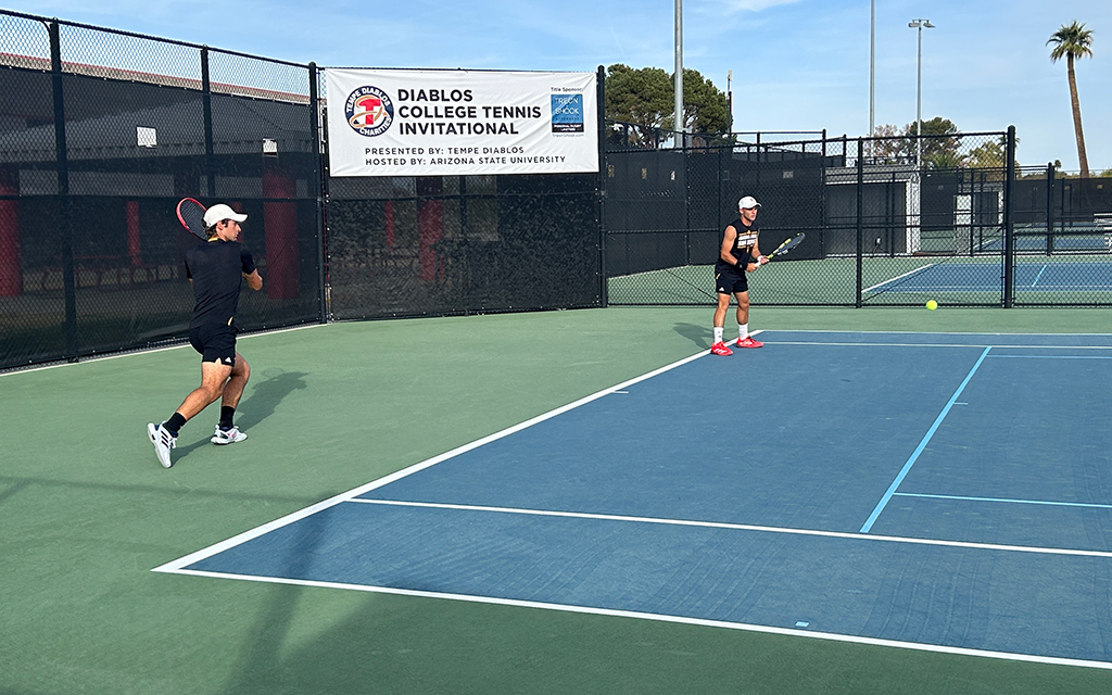 Nikola Cigna and Mathis Bondaz playing tennis on an outdoor court, with a banner for a college tennis invitational in the background.