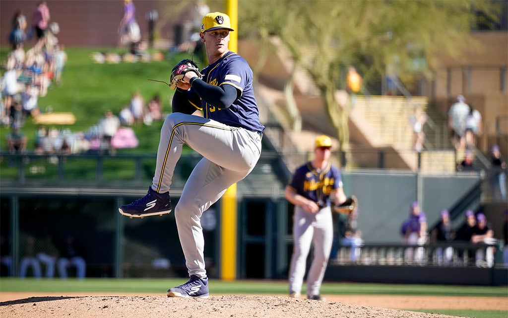 Craig Yoho in navy and yellow uniform on mound, with another player in background.