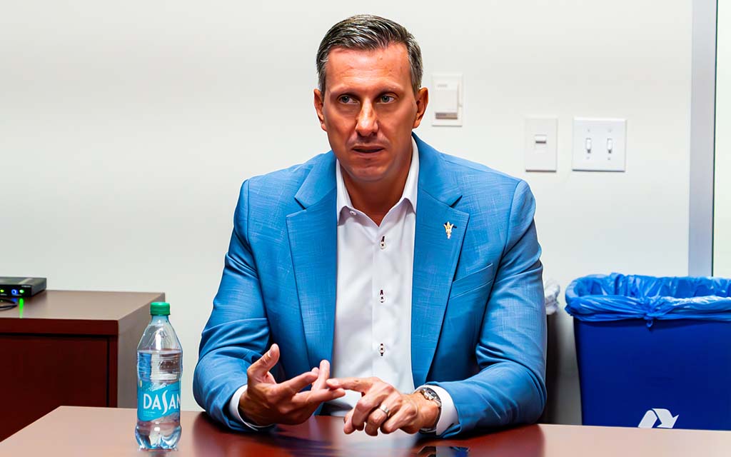 Graham Rossini in a light blue suit seated at a table.