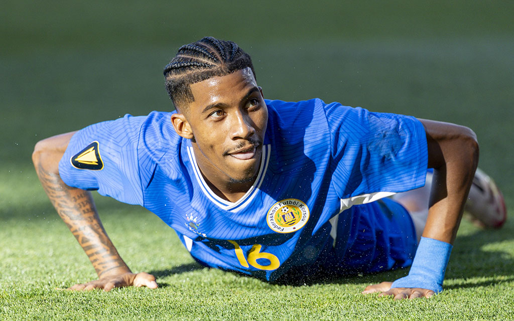 Curacoa's Jearl Margaritha in a blue jersey lying on the grass with focus.