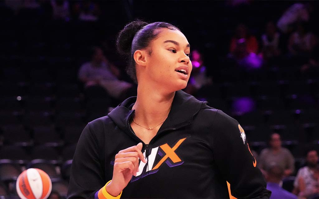 Satou Sabally wearing a black jacket with in orange and purple, looking to the side.
